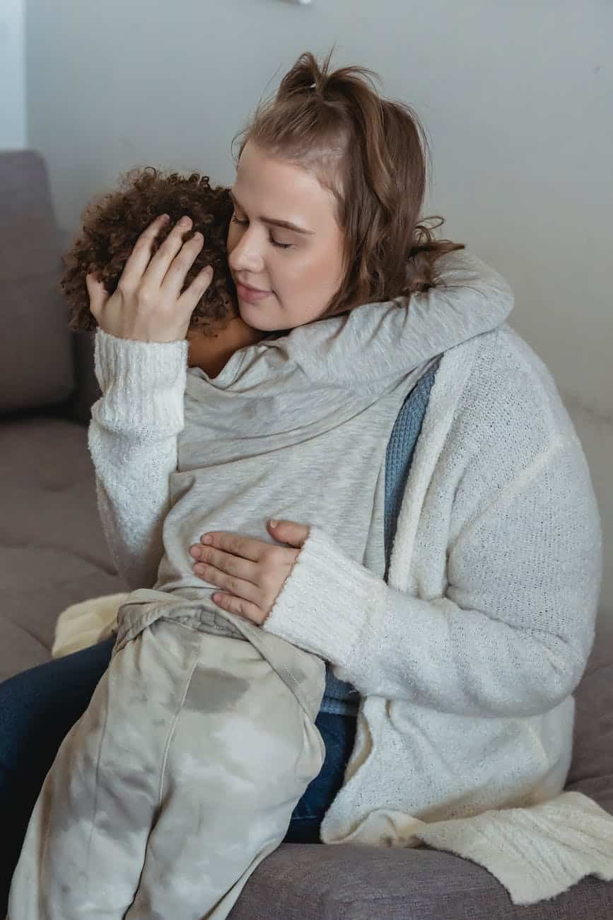 loving mother comforting crying son on couch